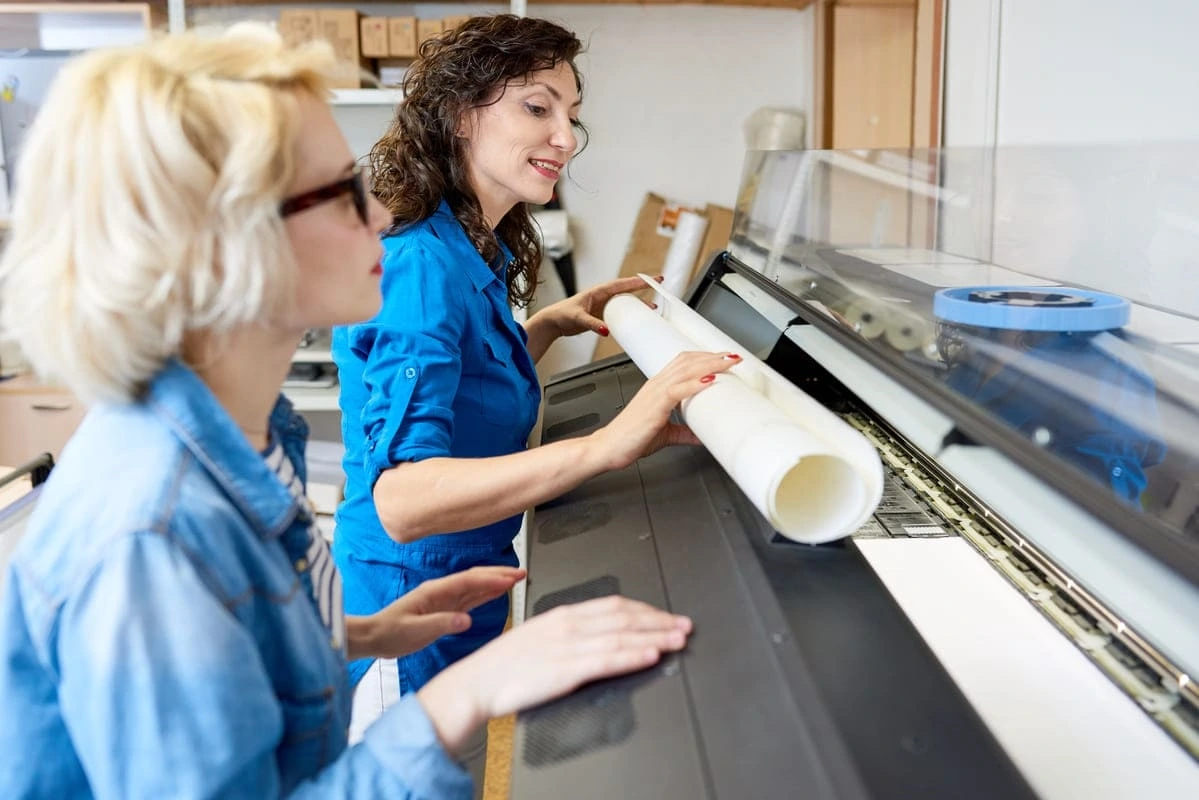 Impresión digital; dos mujeres manipulando una máquina de impresión