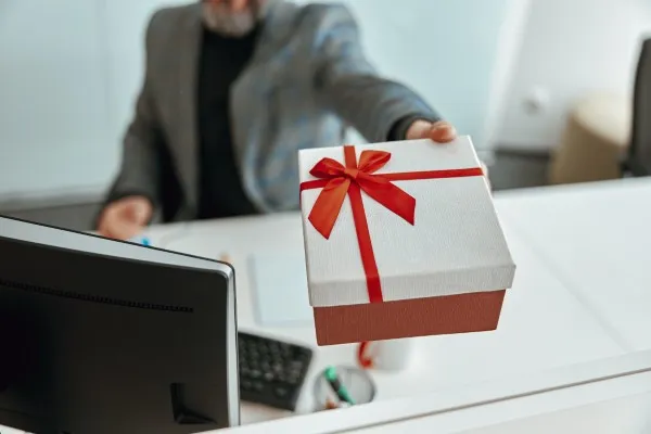 Regalos corporativos en manos de un jefe durante la temporada navideña, destacando el valor de reconocer el esfuerzo y compromiso del equipo. Jefe entregando regalos corporativos en Navidad para fortalecer las relaciones laborales y mostrar agradecimiento a su equipo.
