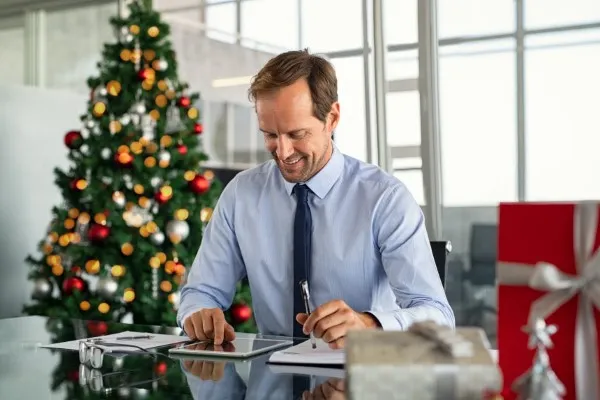 Empresario con espíritu navideño entregando regalos corporativos, fortaleciendo las relaciones laborales y fomentando un ambiente de trabajo positivo