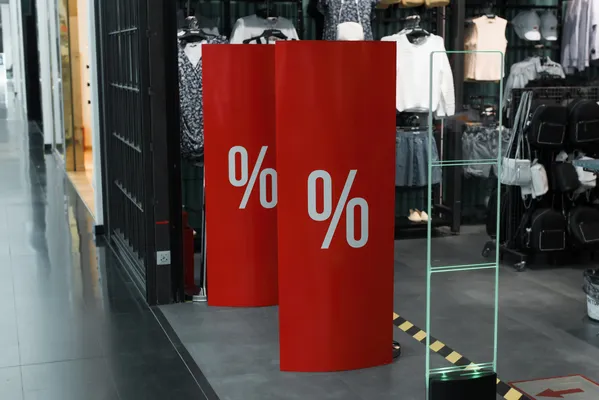 Foto de un banner roll up medidas en una tienda de ropa, están de color rojo y signos de porcentaje