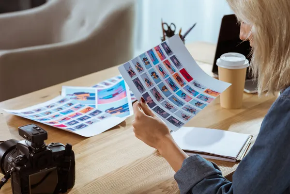 Foto de mujer sosteniendo un tabloide y revisando el resultado de su impresión digital de imágenes a color.