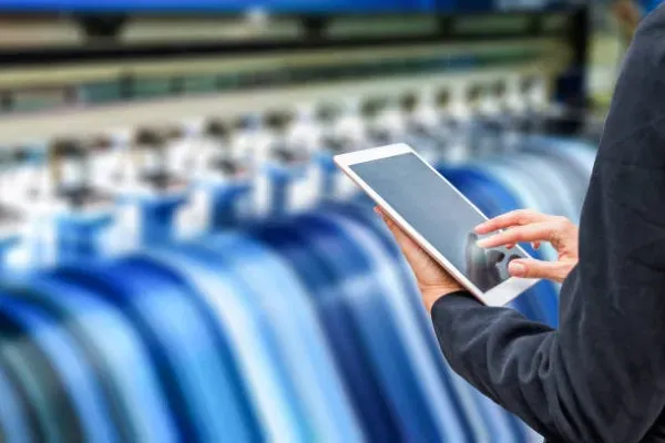 Foto de manos de una persona con una tableta en una imprenta que lee sobre qué es impresión digital