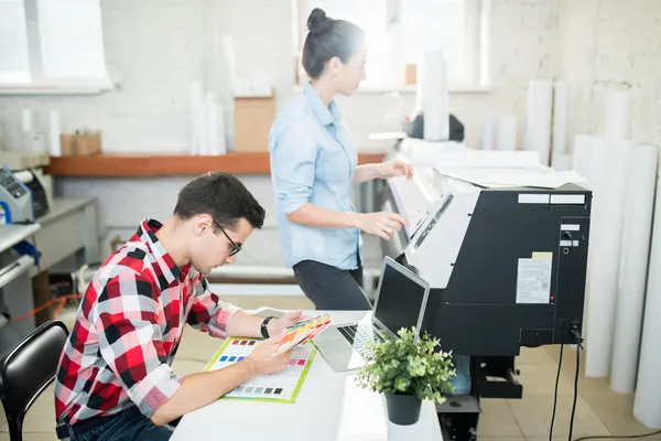 Foto de dos personas en una oficina realizando el diseño personalizado de un tabloide de Impresos César