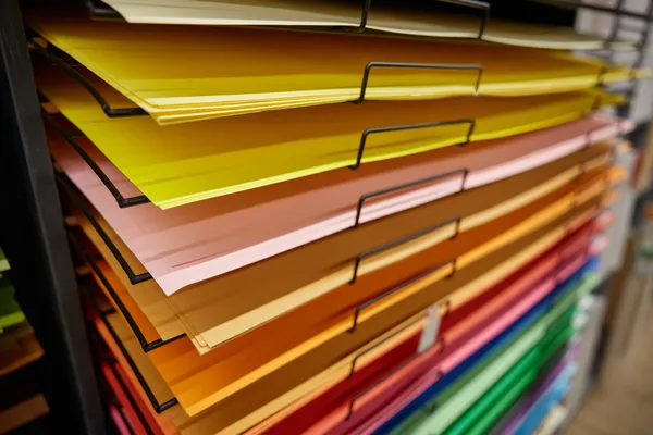Foto de estantes con tabloides de distintos colores dentro de la imprenta de Impresos César