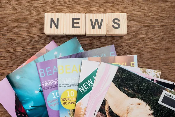 Foto de tabloides de revistas con distintos diseños sobre una mesa de madera y arriba dice NEWS