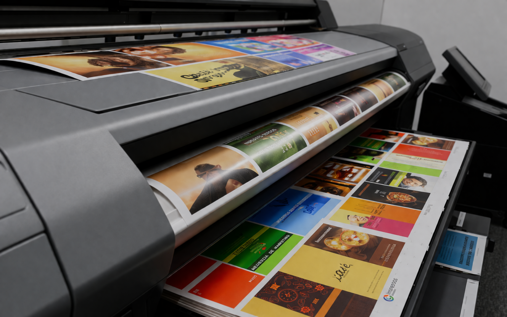 Máquina de impresión digital produciendo materiales gráficos con diferentes diseños y colores definidos.